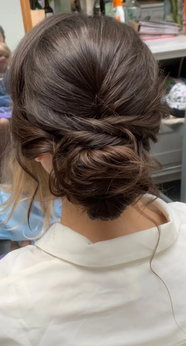 Back view of a textured, voluminous low bun on brunette hair